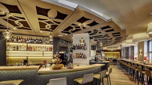 Un área de bar moderna con mostrador, asientos y una variedad de botellas.