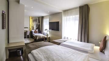 A hotel room with two beds, a desk, a chair, a TV mounted on the wall, and a window with curtains.