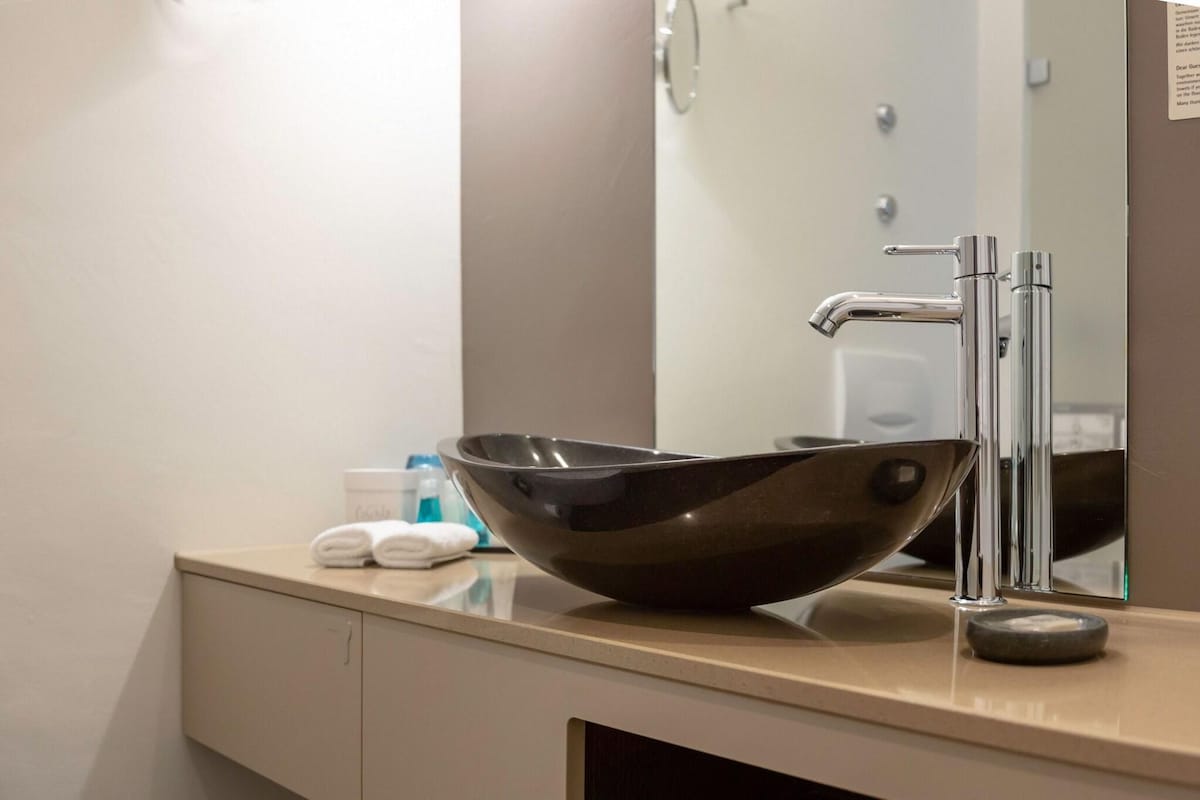 Un baño moderno con un espejo grande, un elegante lavabo negro y un diseño minimalista.