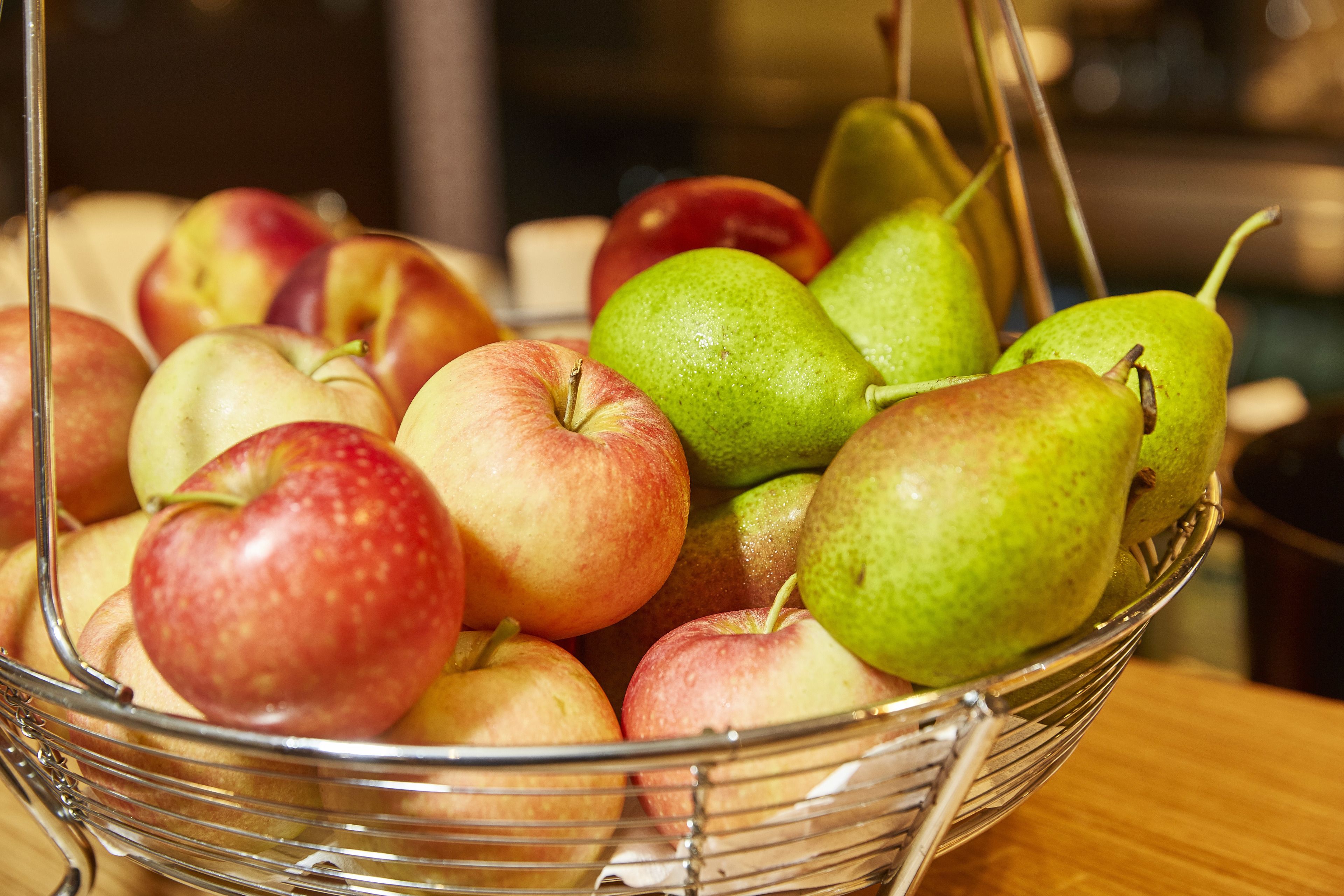 A clear view of a fruit basket containing apples and pears.