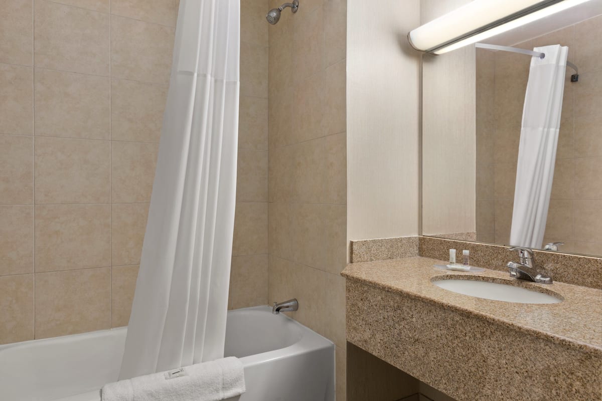 A bathroom with a bathtub, a sink, and a mirror.
