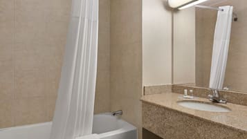 A bathroom with a bathtub, a sink, and a mirror.