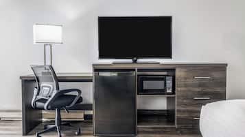 A modern hotel room with a desk, chair, television, microwave, and a bed.