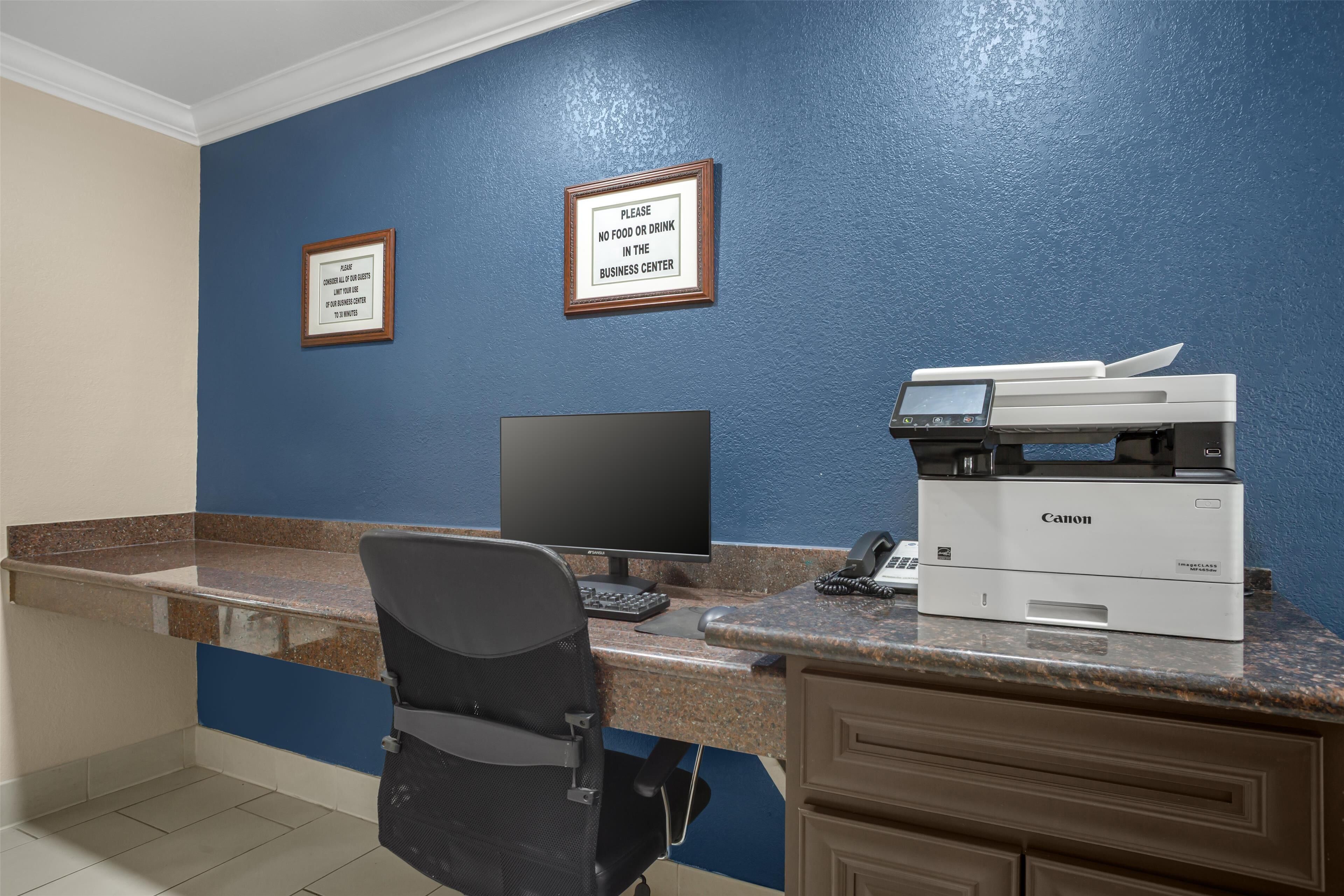 Una recepción con un ordenador, una impresora y carteles enmarcados en la pared.