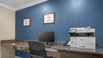 Una recepción con un ordenador, una impresora y carteles enmarcados en la pared.