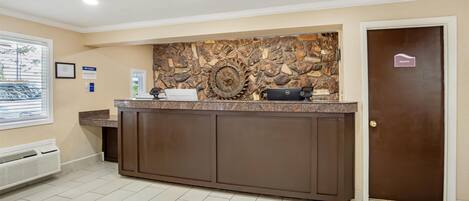 A reception area with a stone wall, a reception desk, a private door, and a window with blinds.
