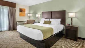 A hotel room with a large bed, two bedside tables with lamps, a chair, a painting on the wall, and a patterned carpet. - Best Western Gold Country Inn (Grass Valley)