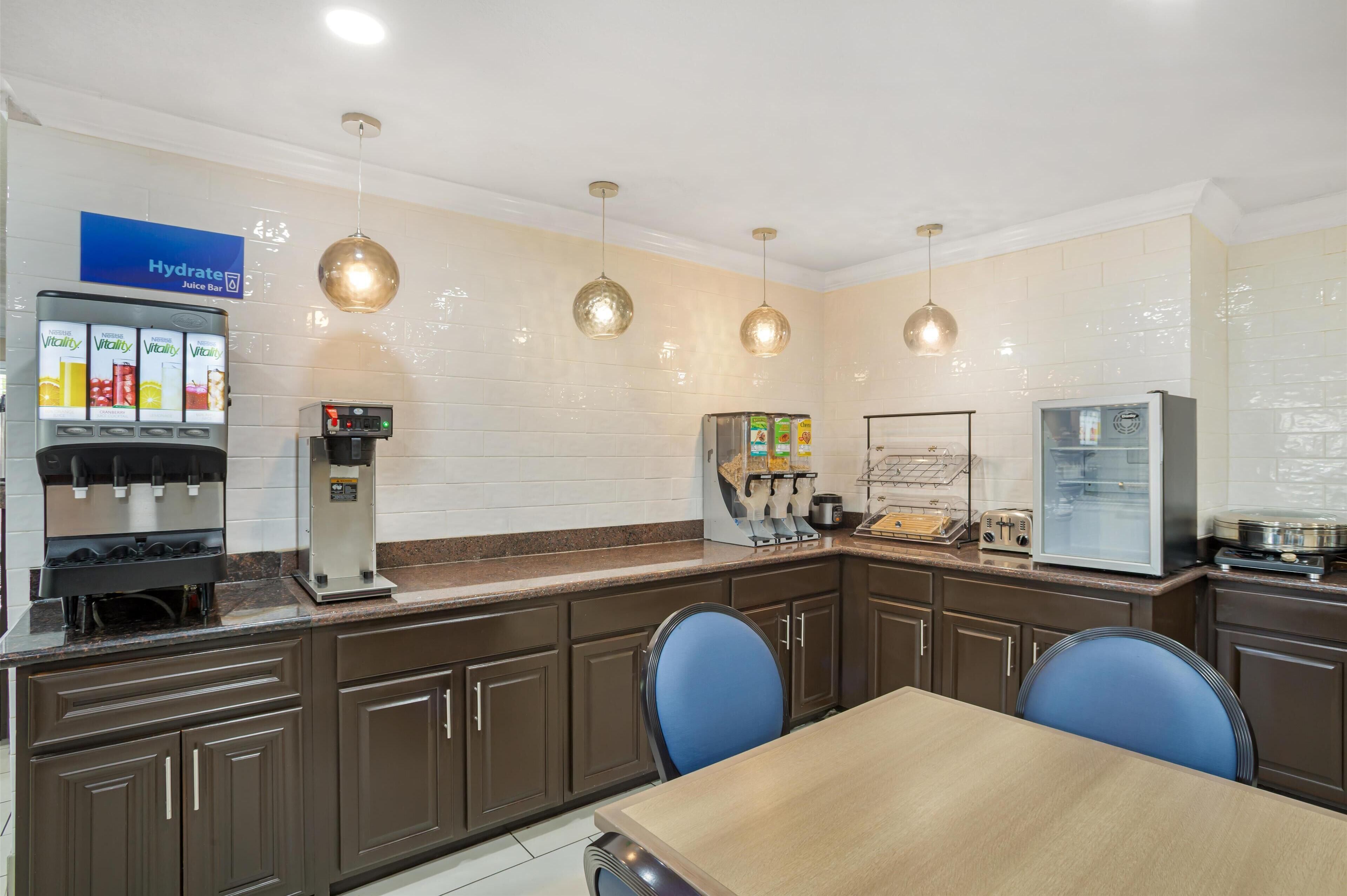 A modern kitchen with a juice bar, a refrigerator, and a microwave.