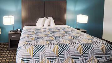 A neatly made bed with a patterned bedspread, two bedside lamps, a nightstand with a phone, and a dark wooden headboard.