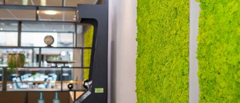 A modern interior with a green vertical garden wall, a counter with various items, and a glimpse of a dining area.
