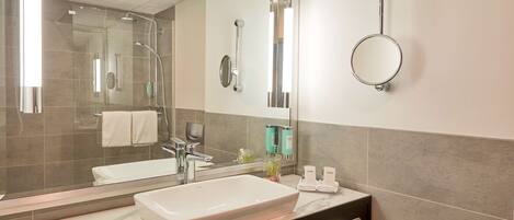 Un baño moderno con un espejo grande, un lavabo y una zona de ducha.