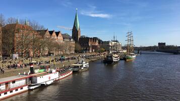 A riverside town with historic buildings, a church tower, and a river with boats.