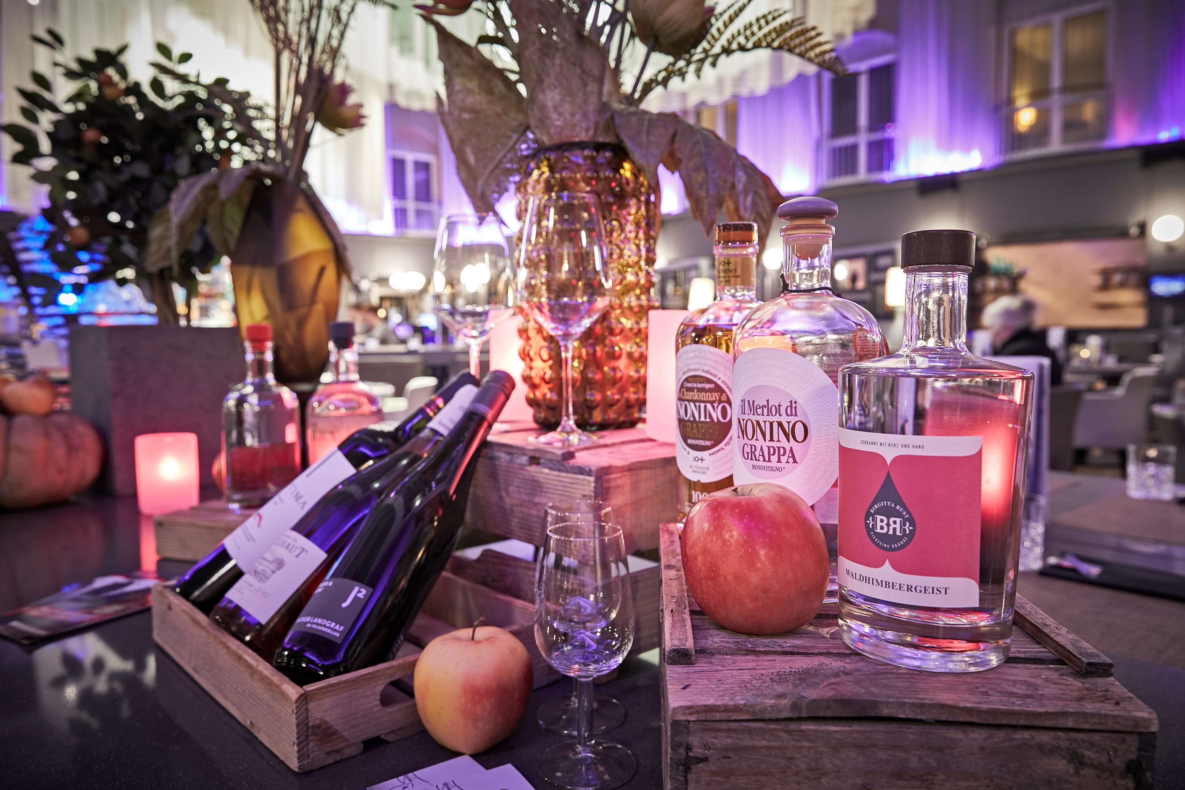 Et bord med vinflasker, glas og et lys.