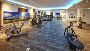 Un gimnasio con bicicletas estáticas, cintas de correr y una pared con una frase motivacional.