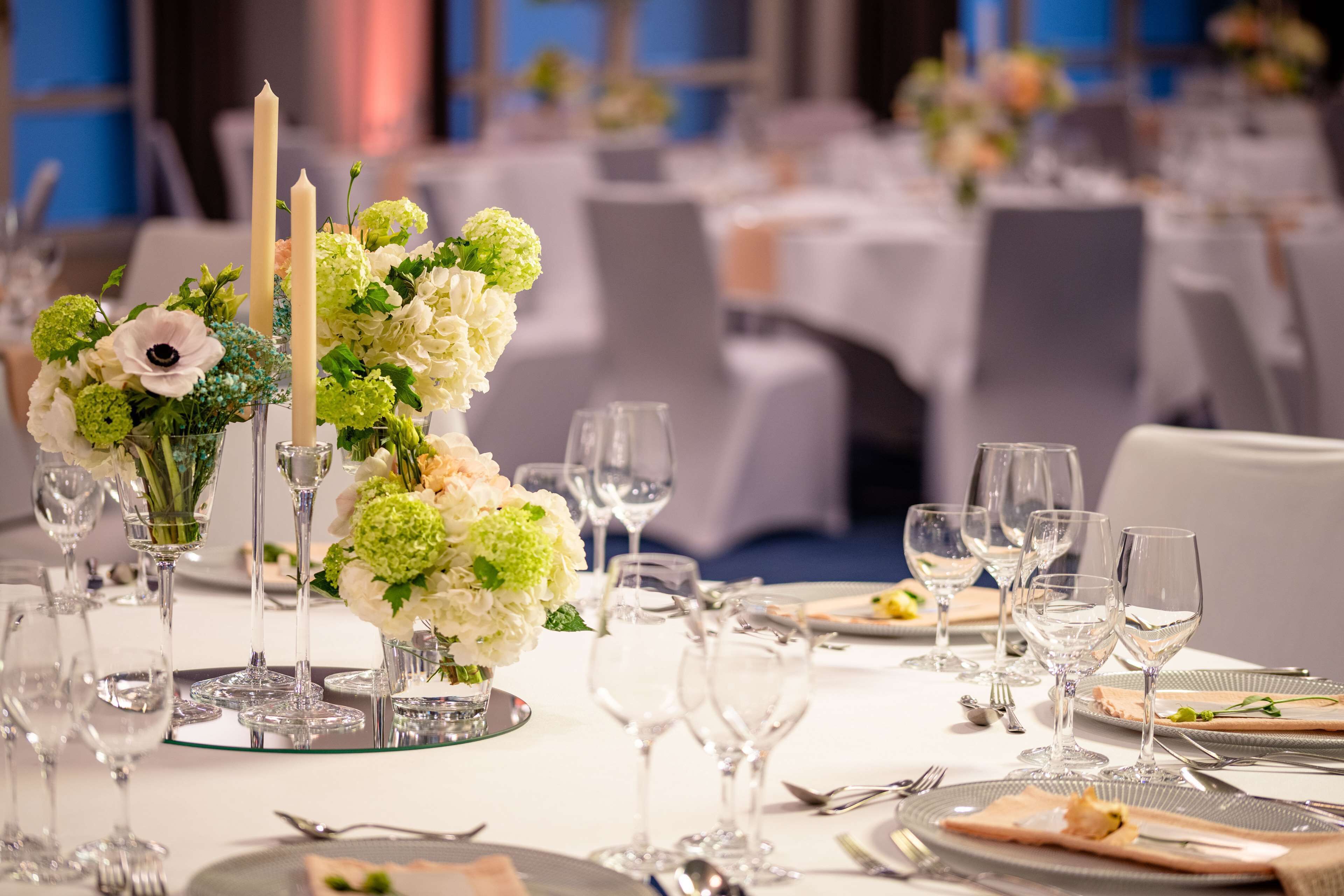 A table set for a formal event with a centerpiece of flowers and candles, surrounded by empty wine glasses and cutlery.
