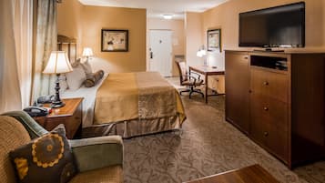 A hotel room with a bed, a desk, a television, and a wardrobe.
