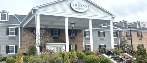 Ein Hotel mit überdachter Einfahrt, einem Schild mit der Aufschrift "The Inn at Lehighburg" und einem angelegten Garten davor.