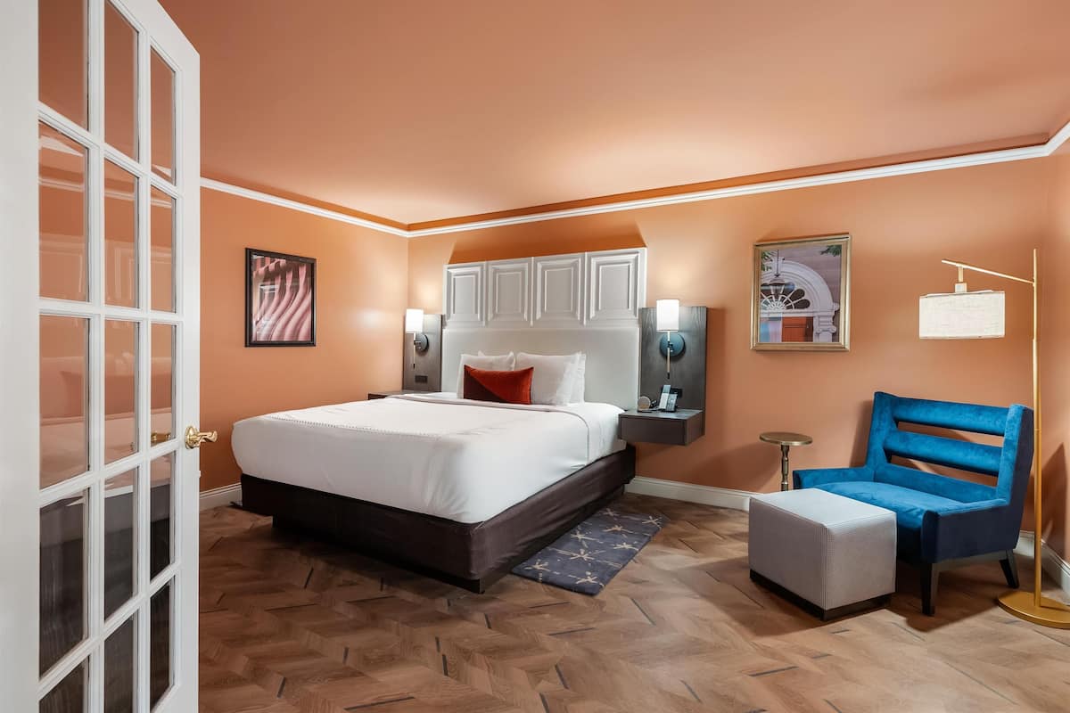 A bedroom with a large bed, a nightstand, a chair, and a floor lamp.