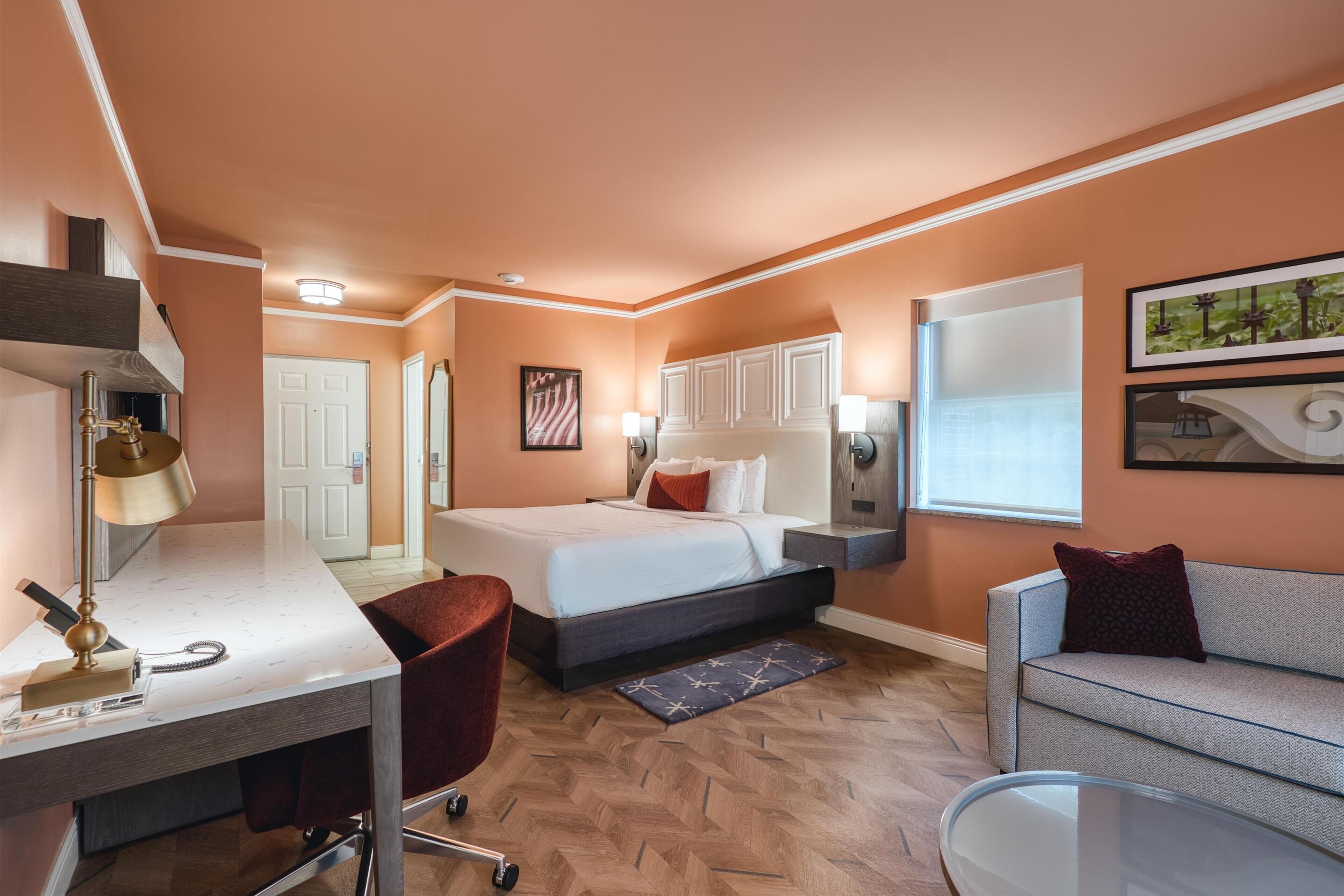 Een hotelkamer met een bed, bureau, stoel en een bank.