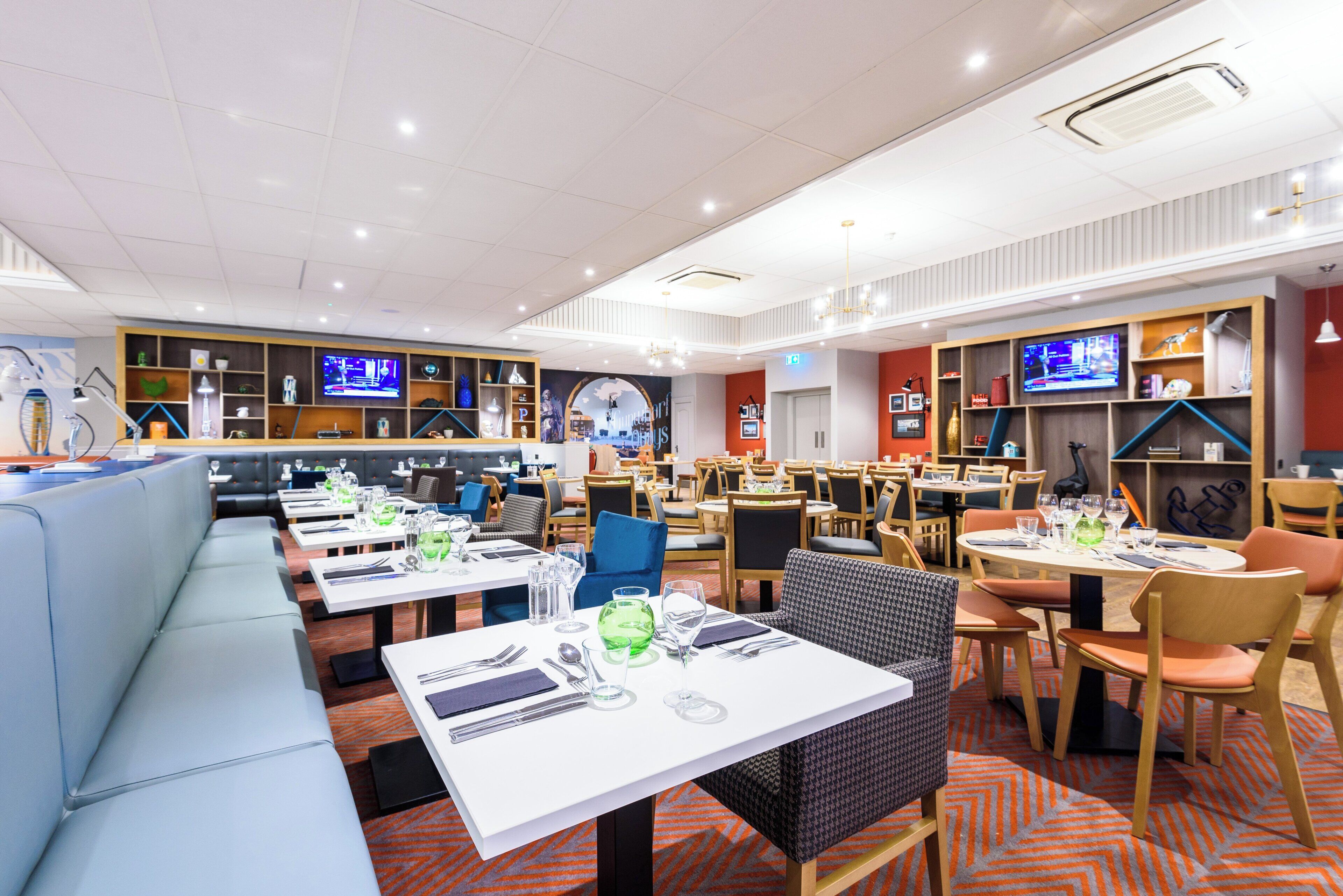 A modern restaurant with multiple dining areas, including booths and tables, and a variety of seating options.