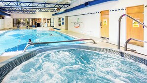 An indoor swimming pool with a hot tub area, a diving board, and a lifeguard stand. - Holiday Inn Portsmouth by IHG (Portsmouth)