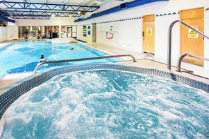 Piscina interna com área de hidromassagem, prancha de mergulho e posto de salva-vidas.