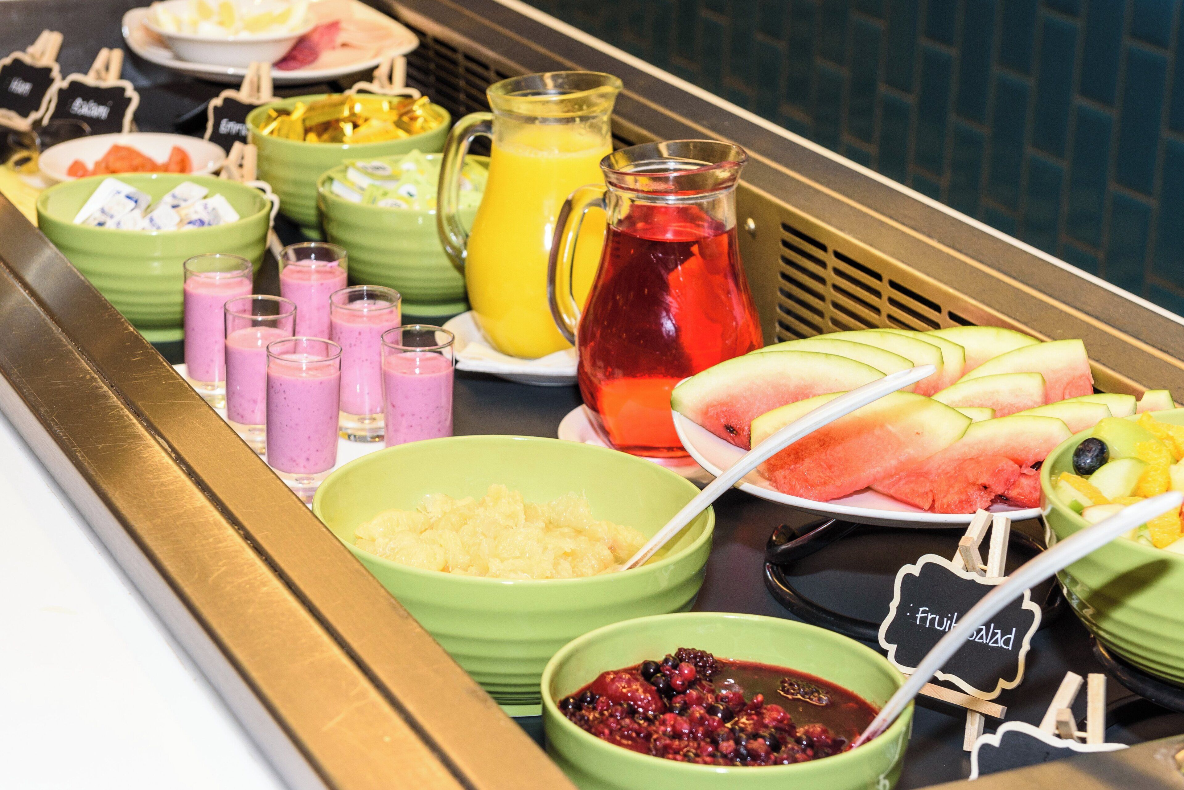 Ein reichhaltiges Buffet mit verschiedenen Speisen, darunter Obst, Smoothies und ein Krug Saft.