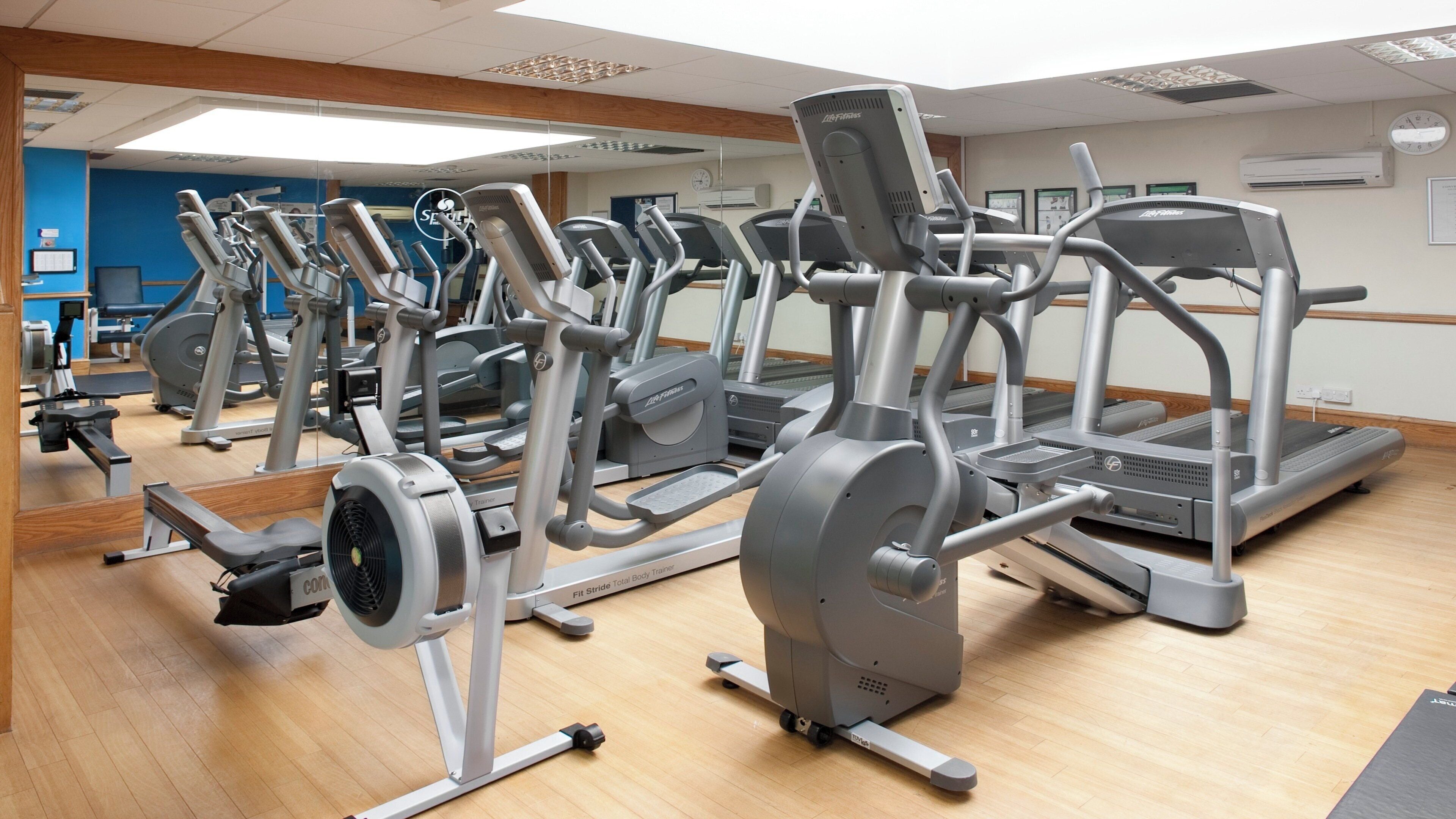 Uma academia com diversos equipamentos de exercício, incluindo esteiras, elípticos e aparelhos de musculação.