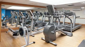 Uma academia com diversos equipamentos de exercício, incluindo esteiras, elípticos e aparelhos de musculação.