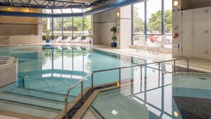 An indoor swimming pool with clear water, a diving board, and lounge chairs. - Holiday Inn Portsmouth by IHG (Portsmouth)