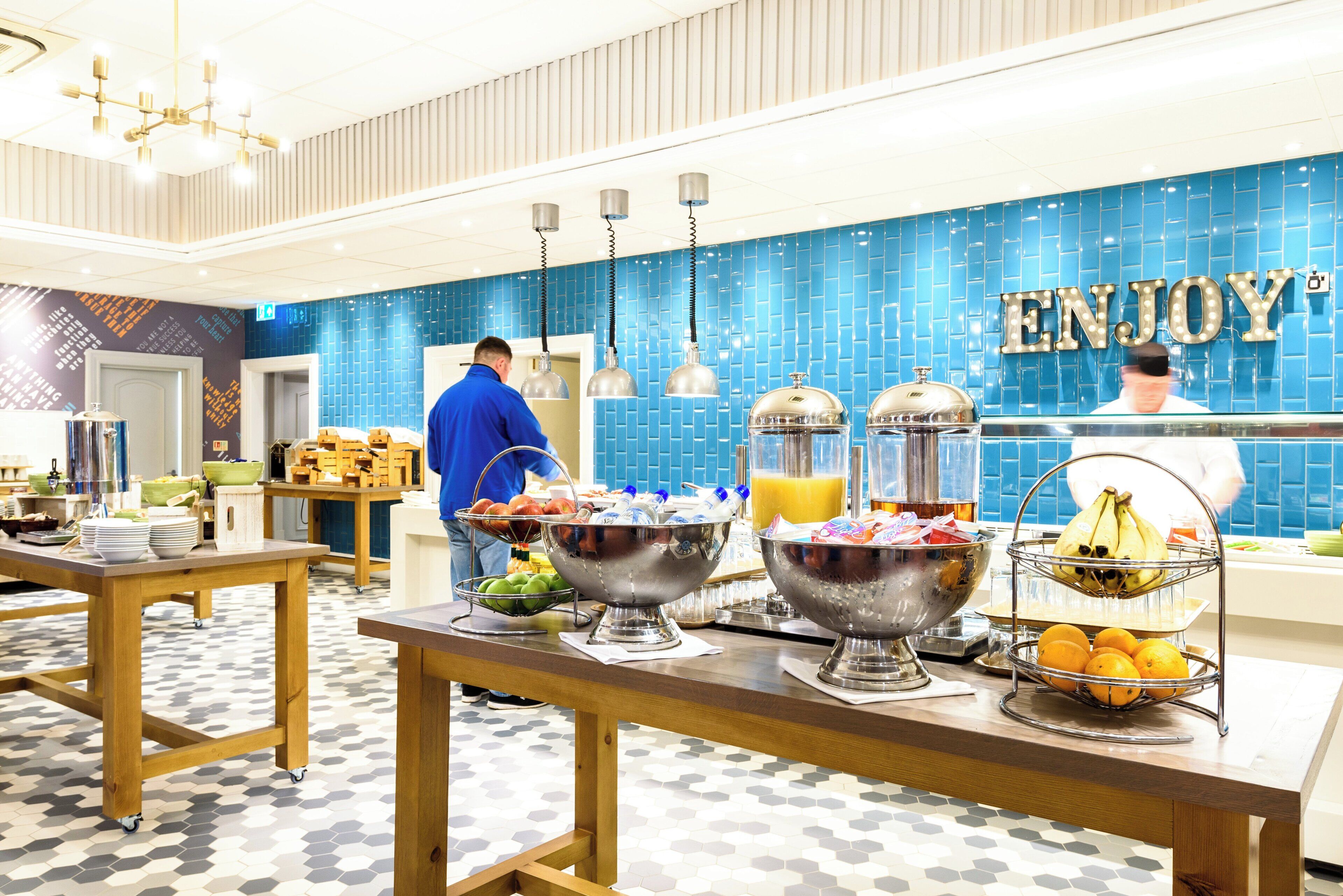 A buffet area with various food items and a blue wall with the word 'ENJOY' in lights.