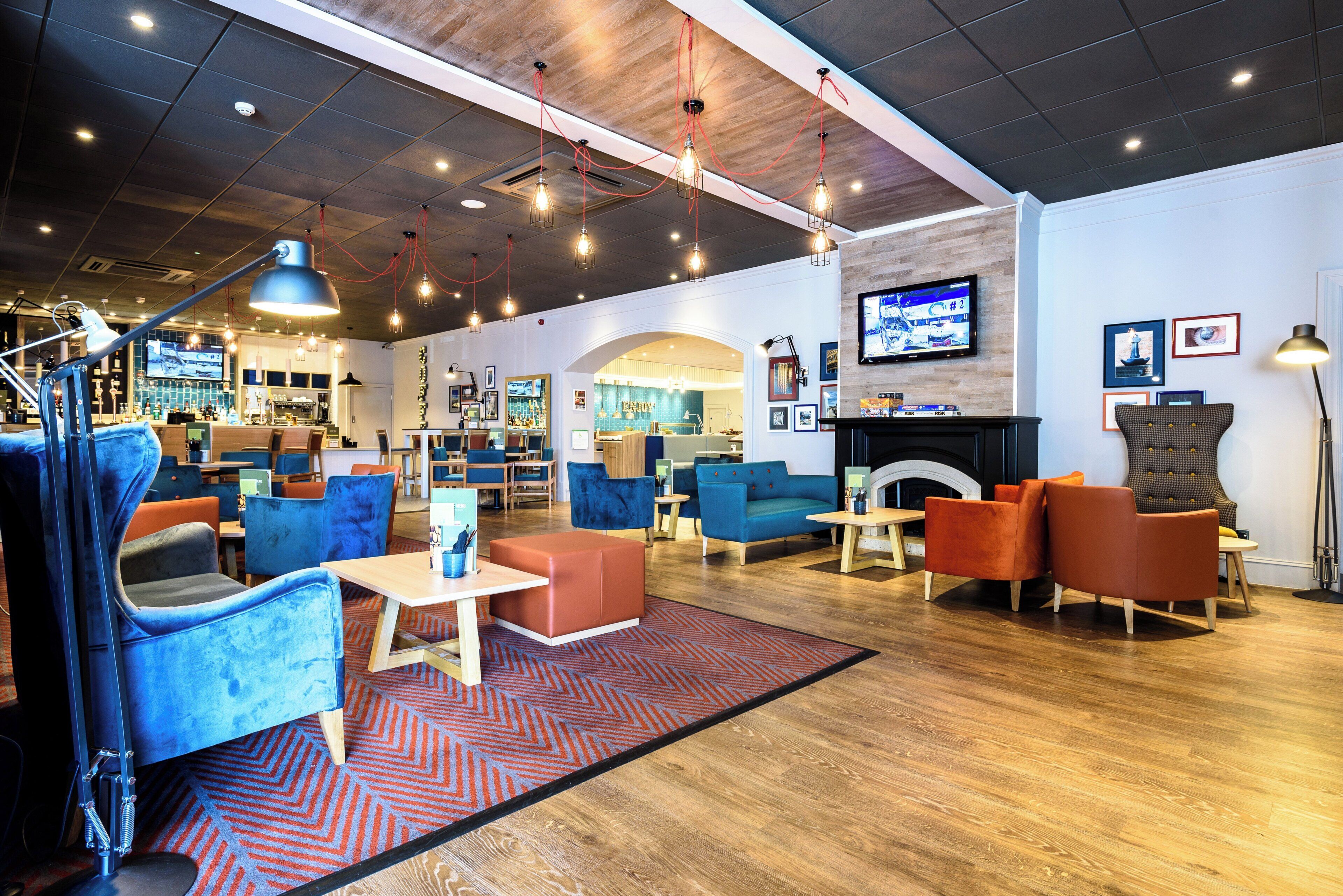 A modern lounge area with seating, a television, and a fireplace.