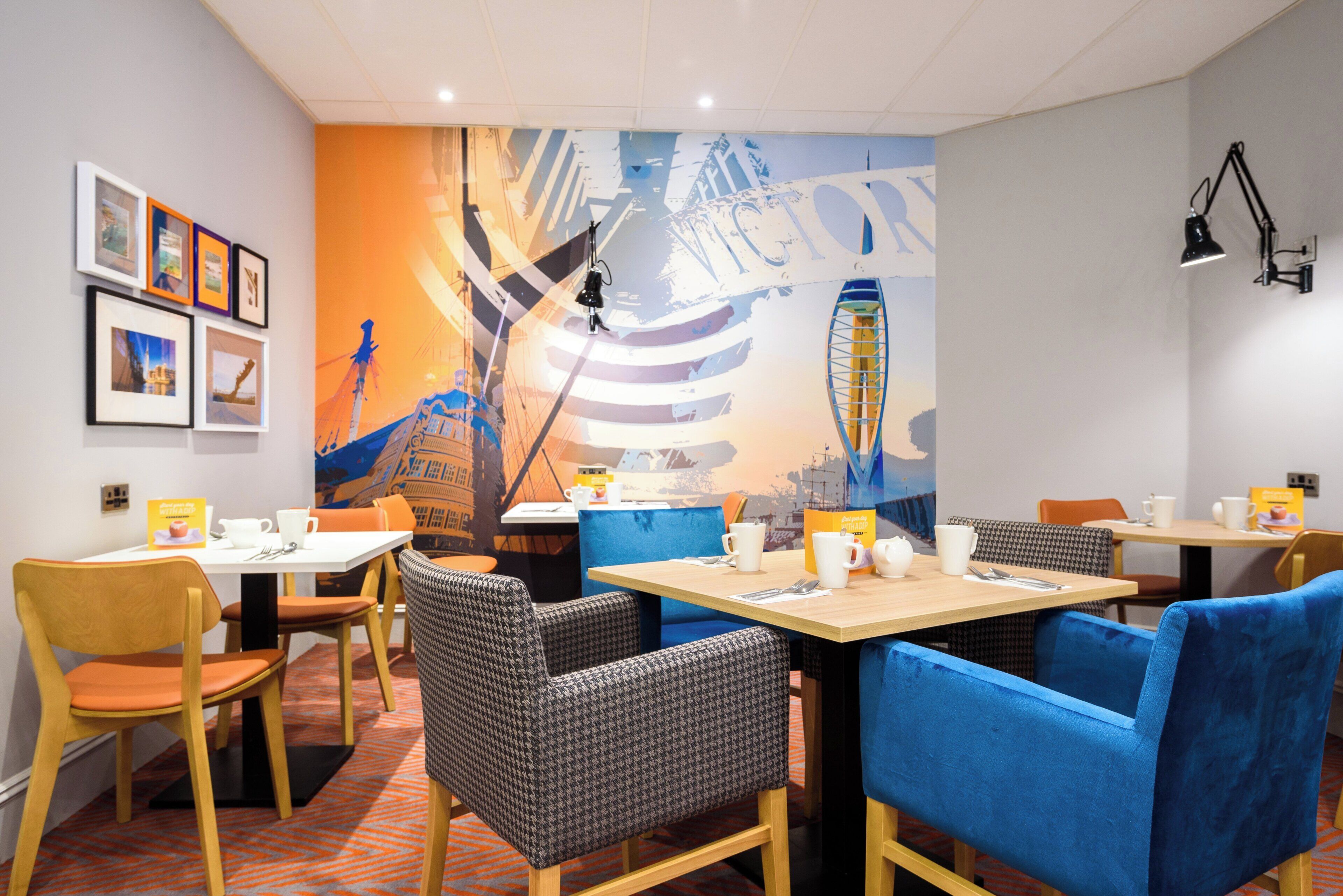 Un comedor moderno con mesas, sillas y un mural en la pared.