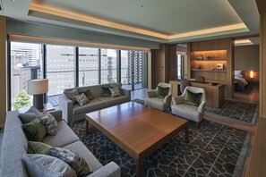 Een moderne hotelkamer met een ruime zithoek, een houten salontafel en een werkplek.