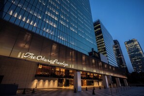 A modern hotel with a prominent glass facade and illuminated signage. - Hotel Okura Tokyo South Wing (Tokyo)