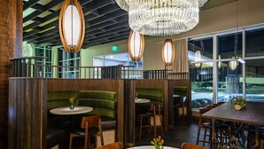 A restaurant interior with booths, round tables, and a chandelier. - Hilton Garden Inn Wausau (Wausau)