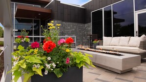 A modern outdoor seating area with a built-in fire feature, surrounded by vibrant flower planters. - Hilton Garden Inn Wausau (Wausau)
