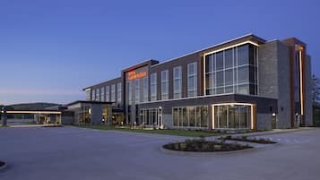 A modern hotel with a prominent sign, large windows, and a well-maintained outdoor area.