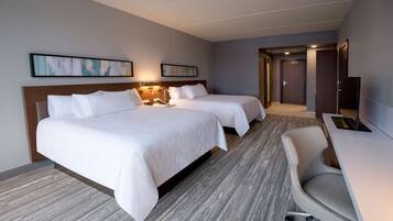 Une chambre d’hôtel avec deux lits, un bureau, une chaise et un téléviseur.