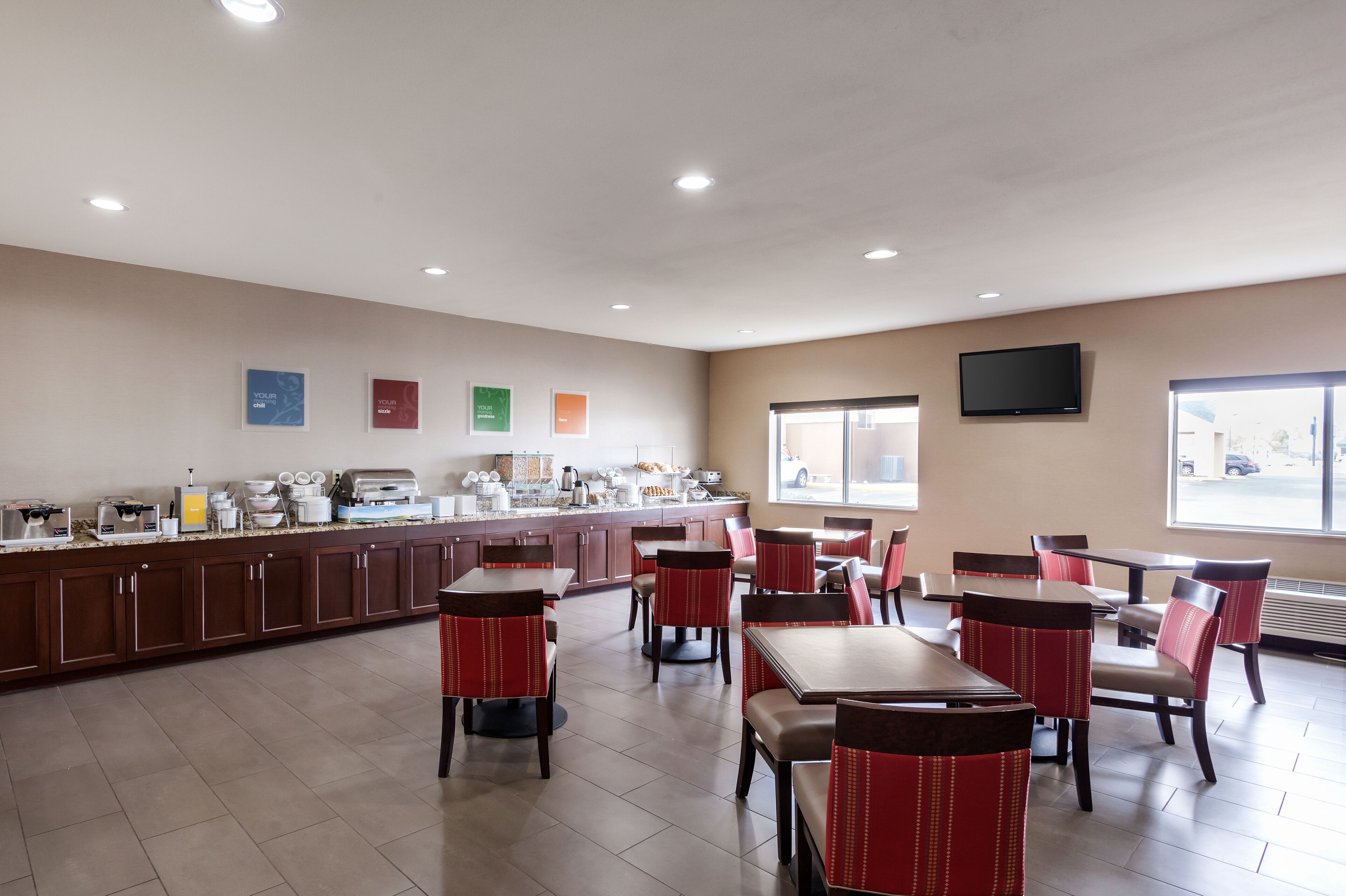 A restaurant with a long counter, multiple tables, and chairs.