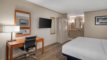 A hotel room with a bed, desk, chair, TV, wardrobe, and bathroom.
