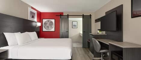 A hotel room with a bed, desk, chair, and a TV.