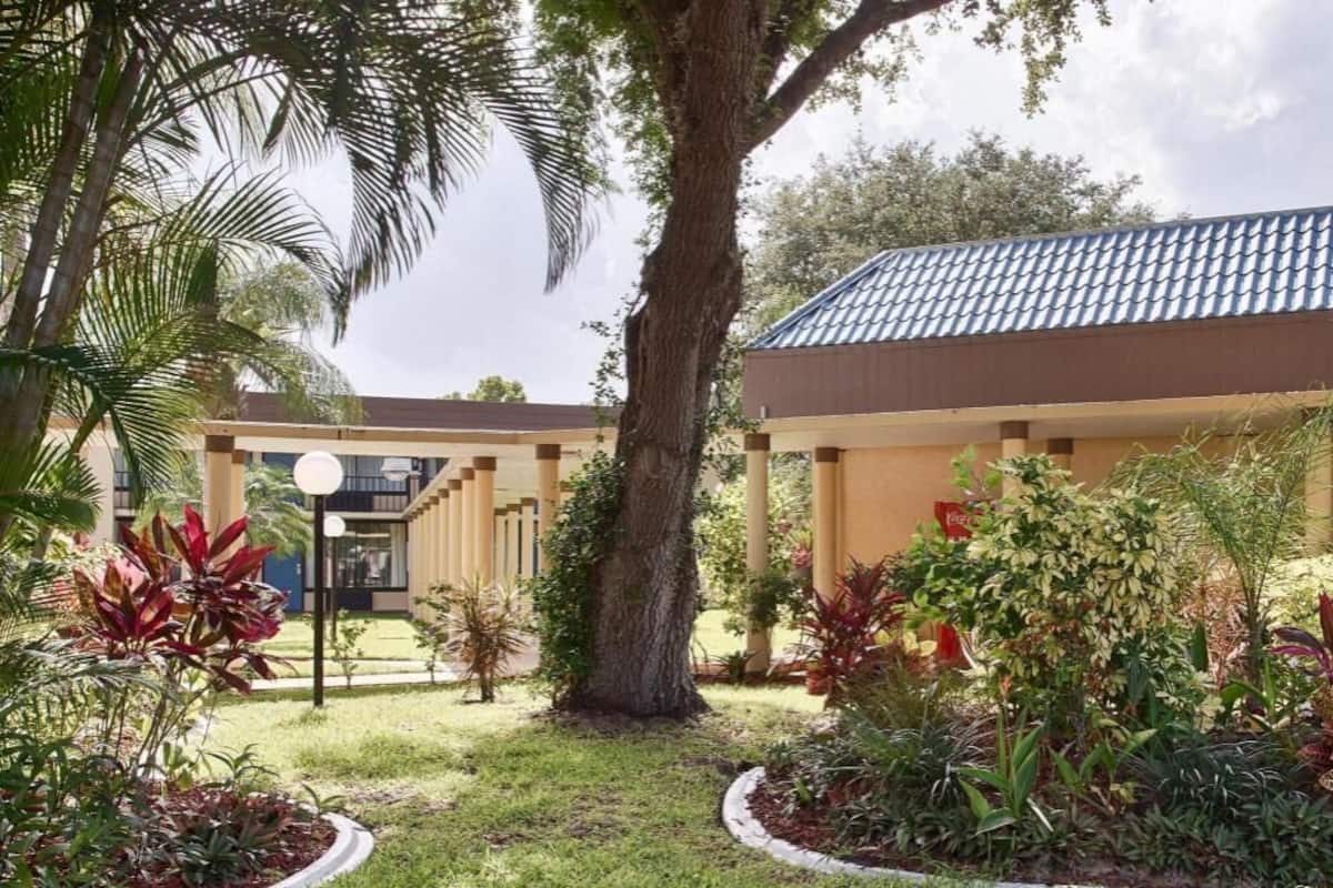 A building with a tiled roof, surrounded by a well-maintained garden with various plants and a large tree.