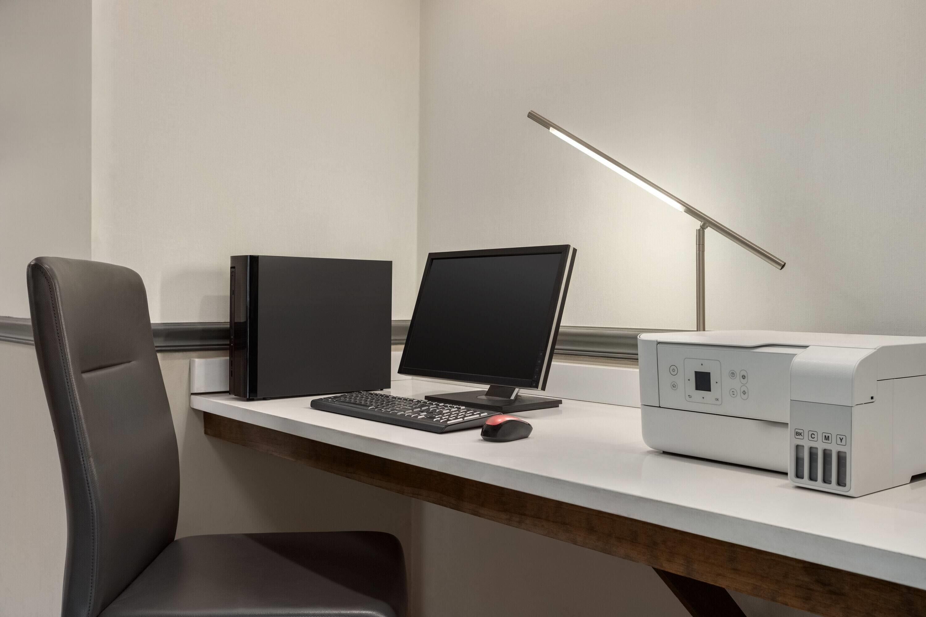 A modern office desk with a computer, keyboard, mouse, and printer.