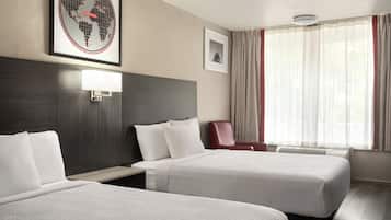 Ein Hotelzimmer mit zwei Betten, einem Schreibtisch, einem Stuhl, einem Wandbild mit einer Weltkarte und einem gerahmten Bild an der Wand.
