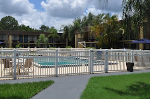 Una piscina al aire libre, sombrillas, sillones reclinables de piscina