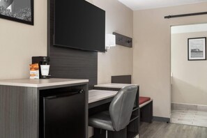Une chambre d’hôtel compacte comprenant un coin cuisine, un lit simple et un petit espace salon.