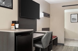 Habitación de hotel compacta con kitchenette, una cama individual y una pequeña zona de estar.