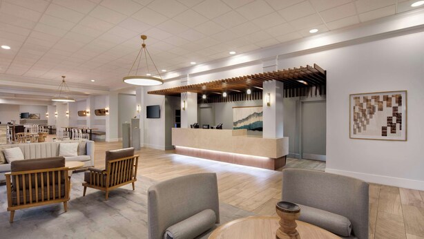 A modern hotel lobby with a reception desk, seating area, and a dining space. - DoubleTree by Hilton Atlanta - Roswell (Roswell)