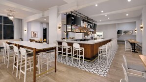A modern hotel lobby with a central bar area, seating arrangements, and a large window providing natural light. - DoubleTree by Hilton Atlanta - Roswell (Roswell)